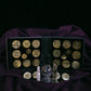 Collection of gold coins in a display case on a dark purple fabric background