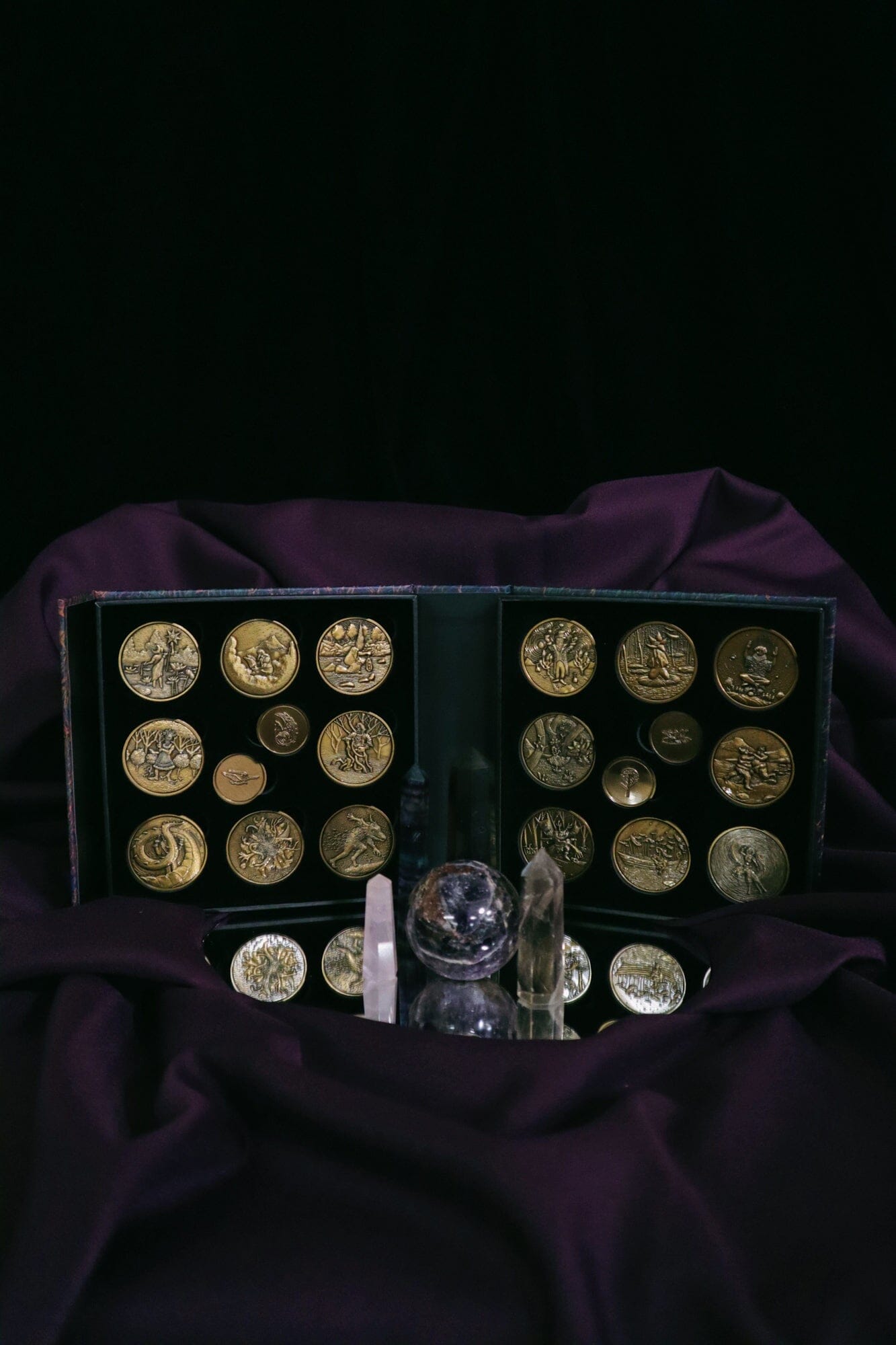 Collection of gold coins in a display case on a dark purple fabric background