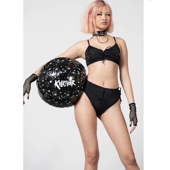 Person wearing a black bikini holding a 'Killstar' inflatable ball on a white background